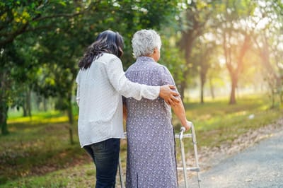 Caregiver assisting an elderly woman in a park