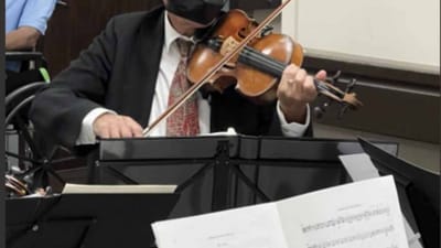 Elderly man playing violin during a group activity