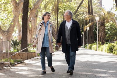 Two seniors walking hand in hand in a park