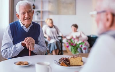 An elderly man enjoying dessert with a friend.