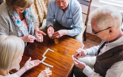 Seniors playing dominoes together at a table.
