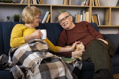 Seniors enjoying company on a couch with a pet