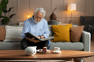 Senior man enjoying tea and cake while looking at a photo album.