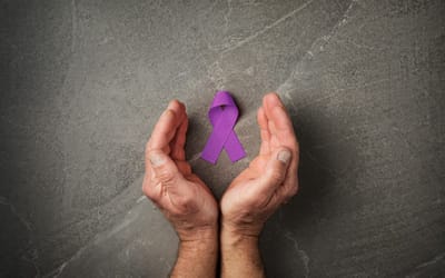 Hands holding a purple ribbon on a textured surface