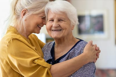 Caregiver embracing an elderly woman with a smile