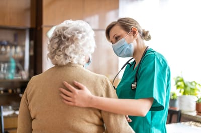 Caregiver assisting a senior resident in a warm setting.
