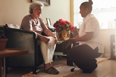 Staff member assisting resident in a cozy living space.