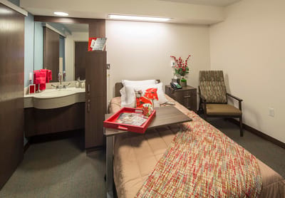 Cozy resident room with a bed and chair.