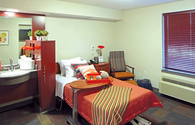 Cozy private resident room with bedside table and flowers.