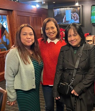 Three women smiling in a social space.