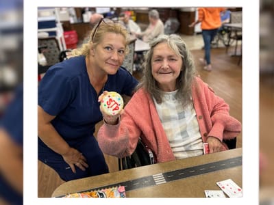 A staff member with a resident holding a decorated cookie