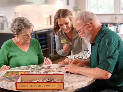 Residents enjoying a puzzle activity with staff in a bright common area