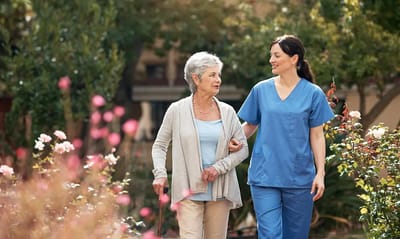 A caregiver and resident walking in a garden