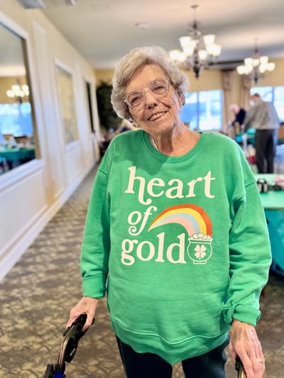 Elderly woman in a common area wearing a bright sweater