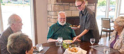 Residents dining together with food served by staff