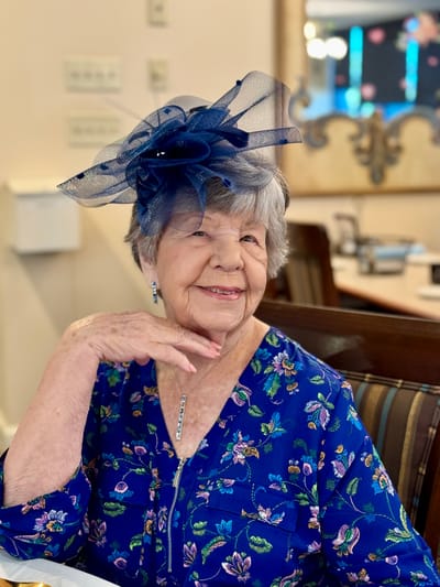 Senior resident posing with a stylish hat at an indoor setting