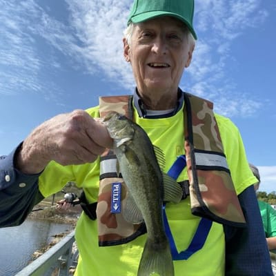 An elderly resident proudly holding a fish outdoors