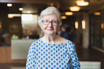 An elderly woman smiling in a common area