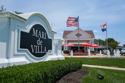Exterior view of Mari De Villa Retirement Center with flags