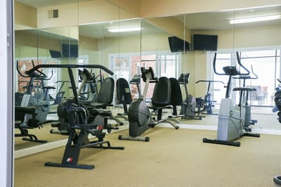 A fitness room with exercise equipment and mirrors
