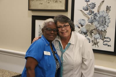 Two staff members smiling together in a lobby area