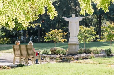 Residents enjoying a serene outdoor space with a statue.
