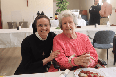 A smiling staff member with a resident at the dining table