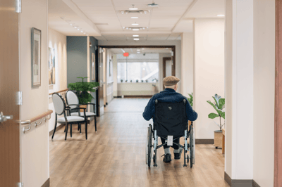 A resident in a wheelchair in a well-lit hallway