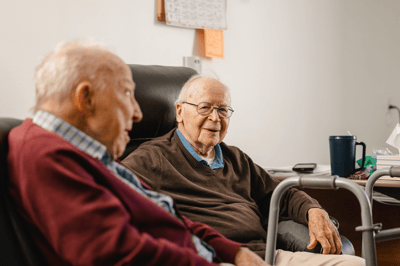 Two elderly men sitting together in a common area