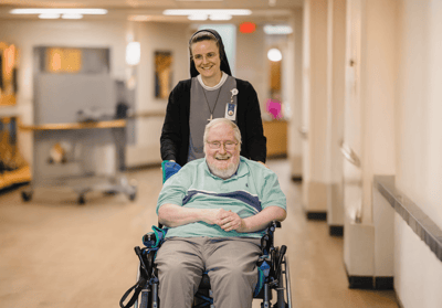 A staff member pushing a resident in a hallway