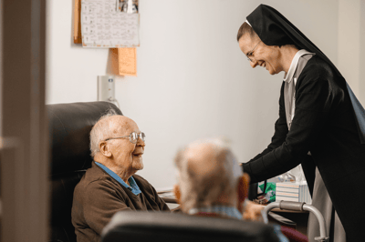 A caregiver interacting with a smiling resident in a room