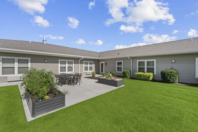 Outdoor seating area with flower beds and green lawn