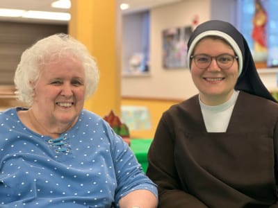 A resident and staff member smiling together