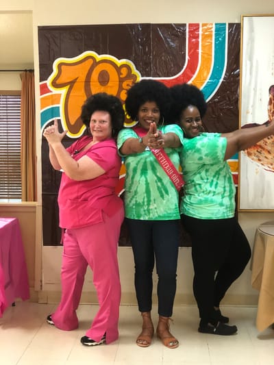 Staff and residents in retro-themed outfits posing together
