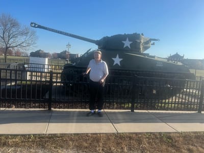 Resident posing next to a military tank in a park