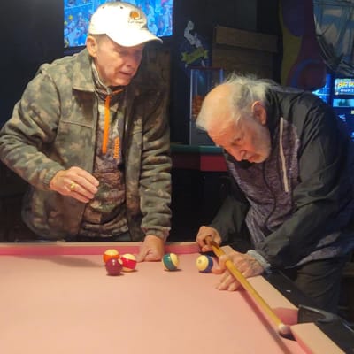 Two residents playing pool in an activity room