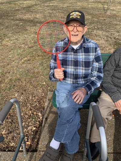 Resident smiling with a tennis racket outdoors