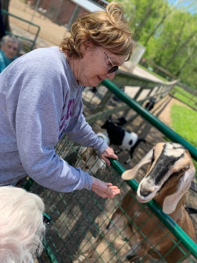 Resident interacting with a goat in the outdoor petting area