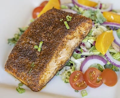 Plate of grilled salmon with salad and tomatoes