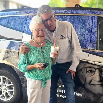 Resident enjoying a treat with staff member next to facility vehicle
