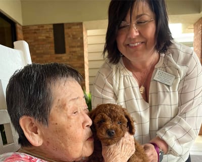 Resident enjoying time with a staff member and a puppy