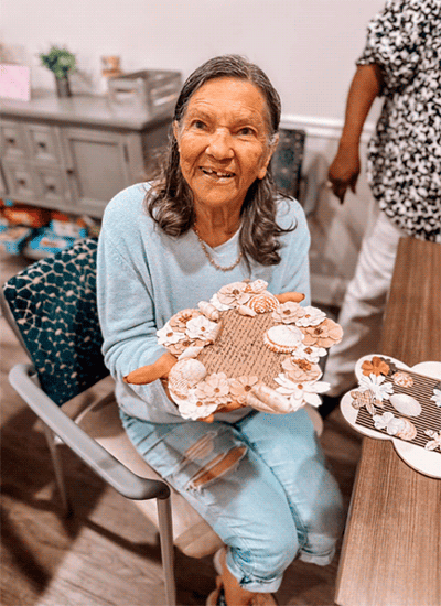 Resident showing a decorative craft project at a table