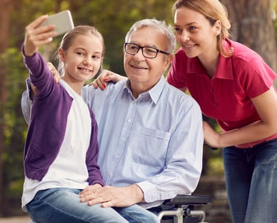 A senior man enjoying a selfie with a girl and a caregiver