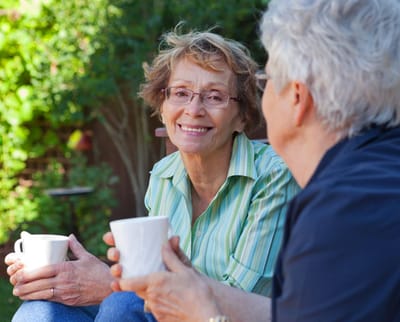 Two residents enjoying coffee outdoors in a garden
