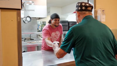 Staff serving food to a resident in the kitchen
