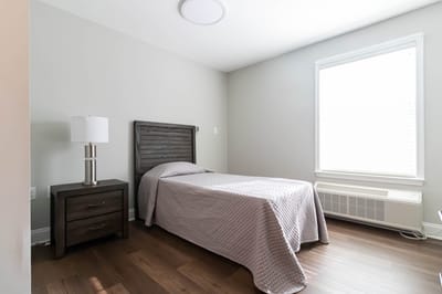 A simple resident room with a bed and lamp