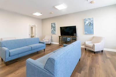 Bright common area with blue sofas and a TV