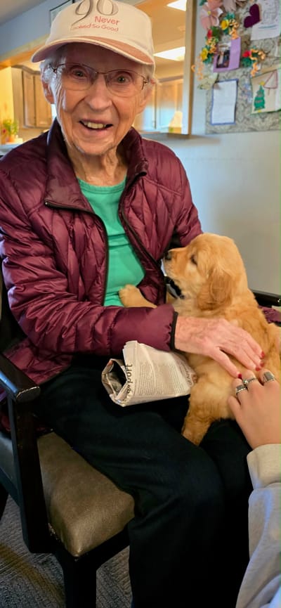 A resident enjoying time with a puppy in a cozy setting
