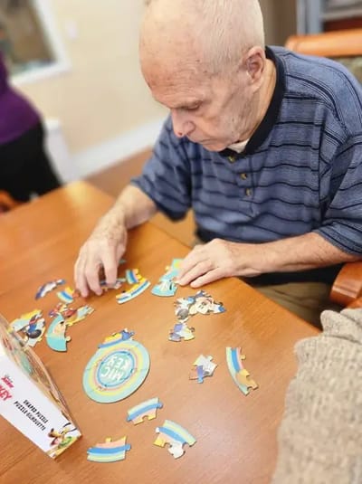 Resident engaged in a puzzle activity at a communal table