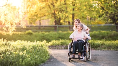 A caregiver pushing a resident in a wheelchair outdoors